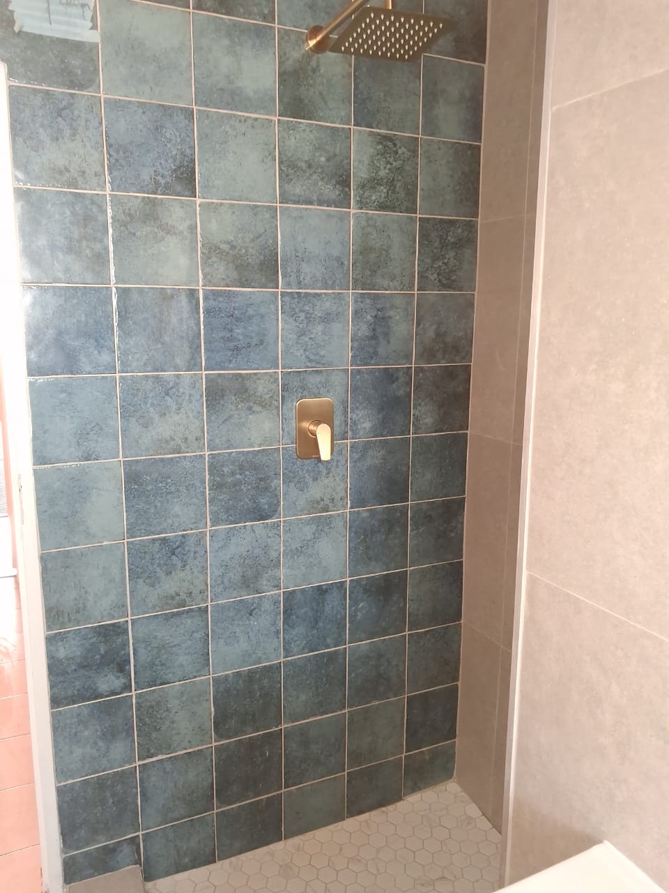 Teal-tiled shower with brushed-gold rainfall head and mixer