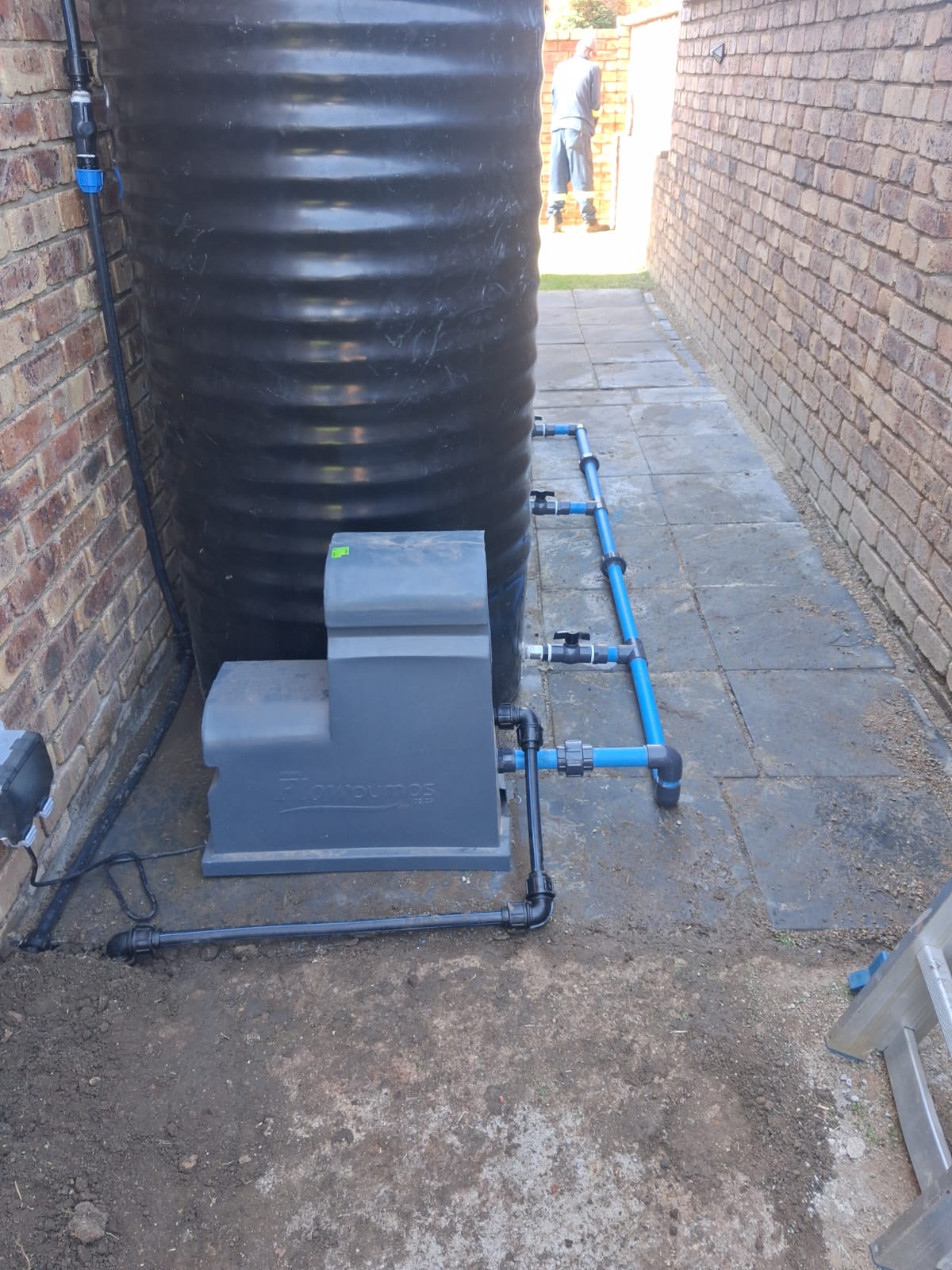 Black Jojo water tank with Flowpumps booster and blue supply pipework