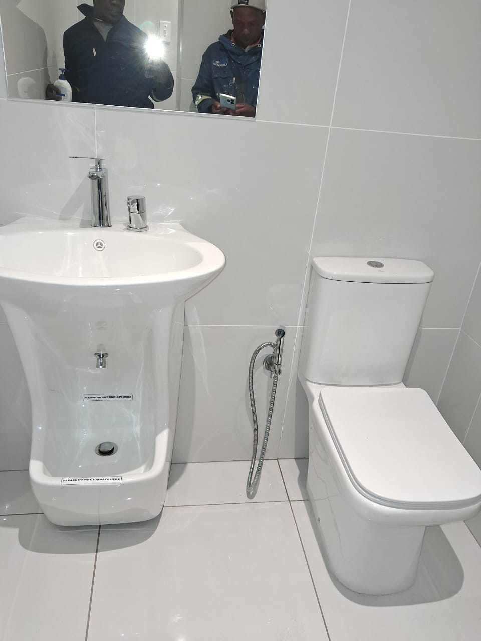 White wudu ablution basin with toilet and handheld bidet sprayer
